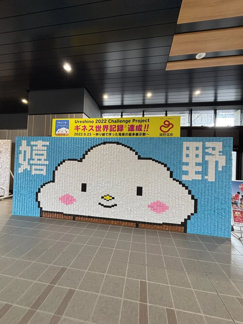 ギネス世界記録達成の看板と、折り紙の電車を並べて作った嬉野の文字と雲のキャラクターの絵