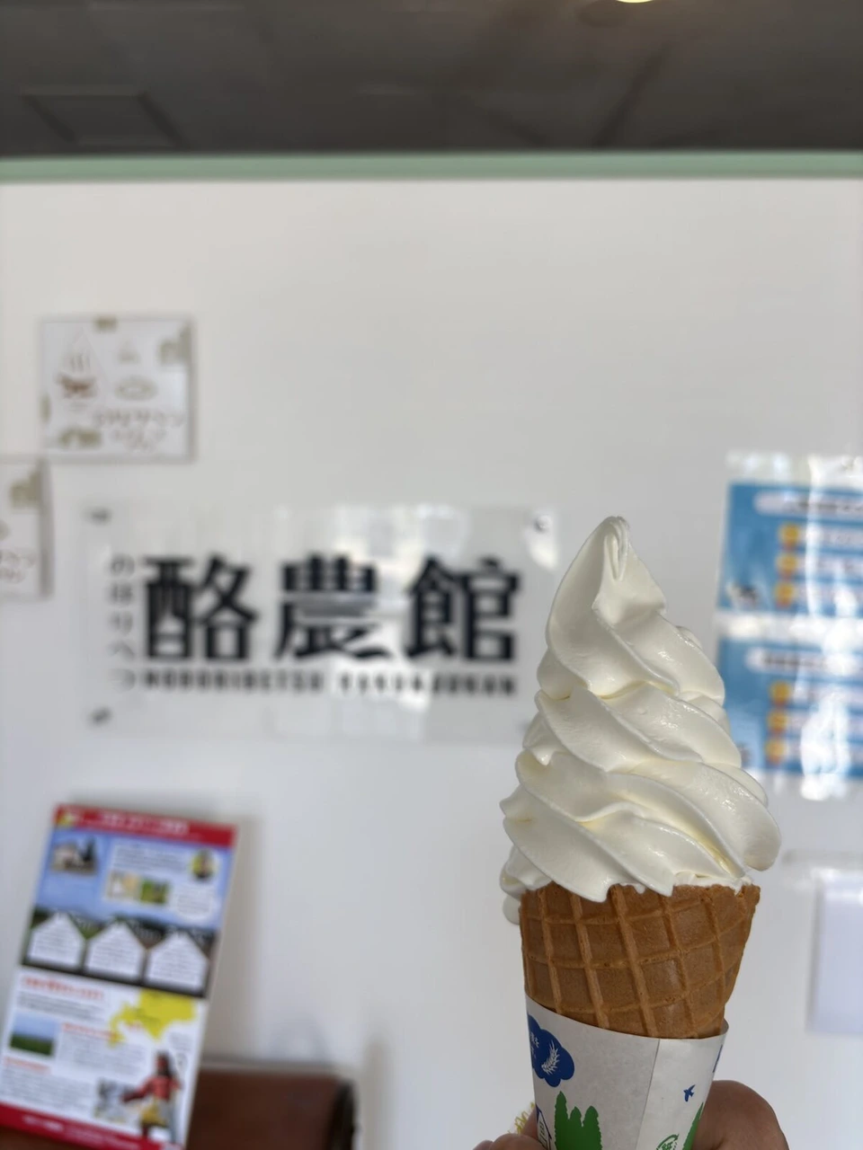 酪農館の文字の前で持ったソフトクリーム