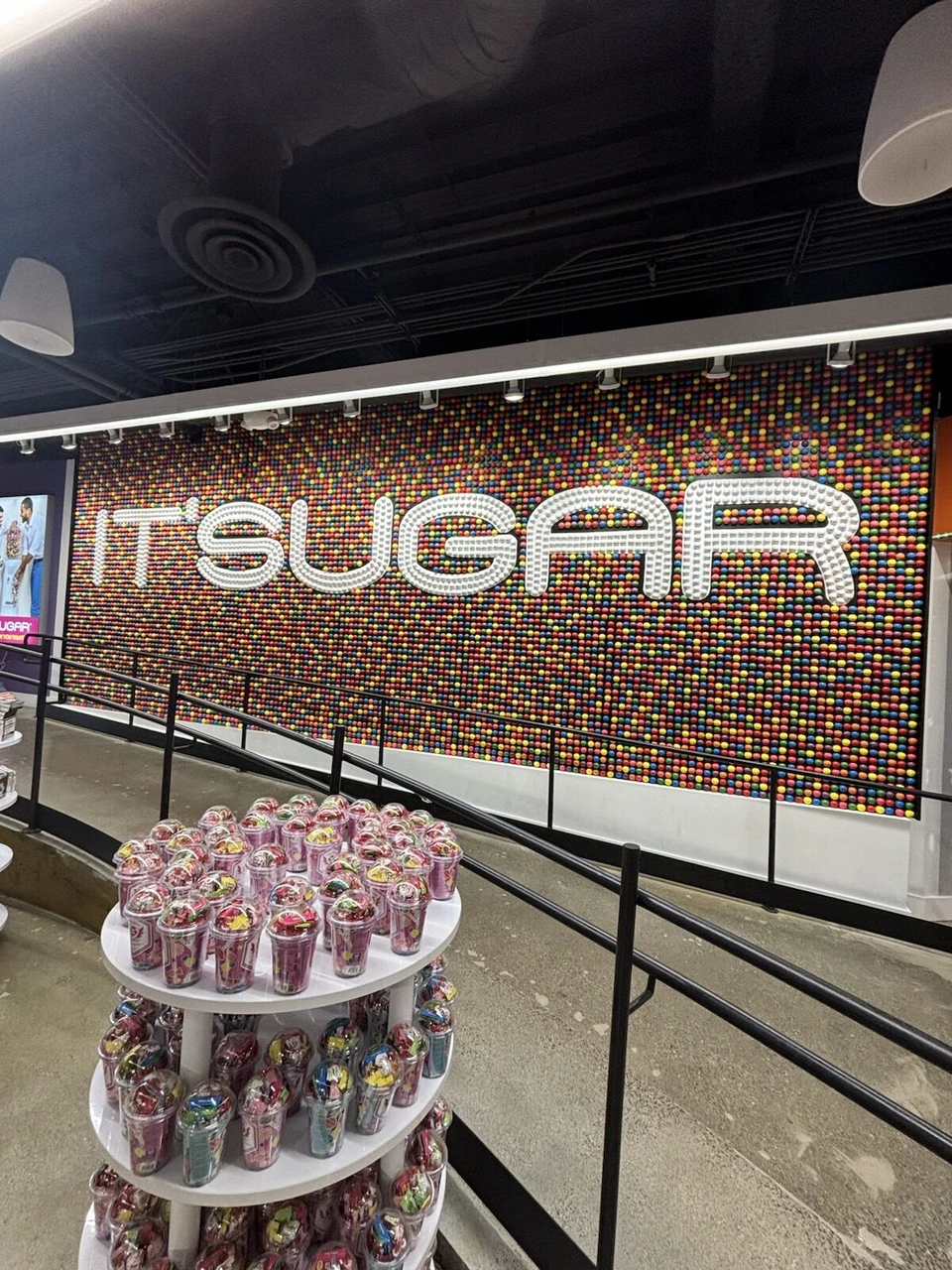 お菓子の店IT'SUGARのカラフルな壁と、キャンディが並ぶ棚