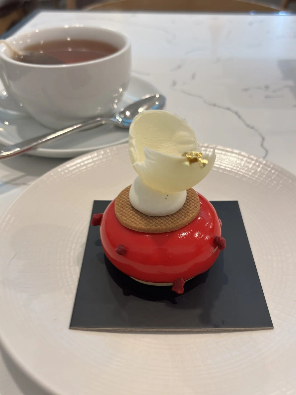 ユニオンスクエア近くのカフェの赤いドーム形のケーキと白いチョコの飾り、紅茶