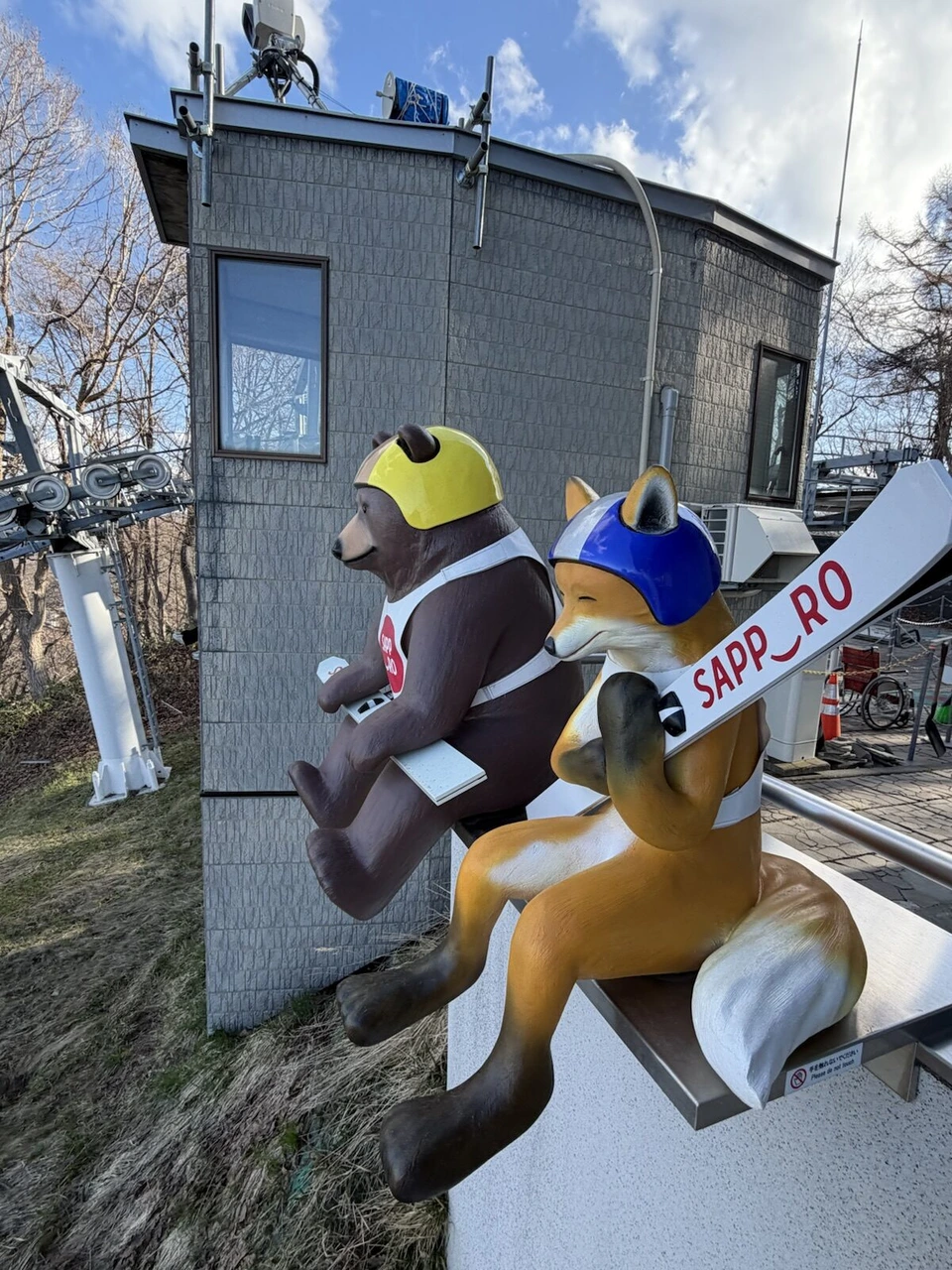 大倉山展望台のジャンプ選手の格好をしたキャラクターの像とSAPPOROの看板