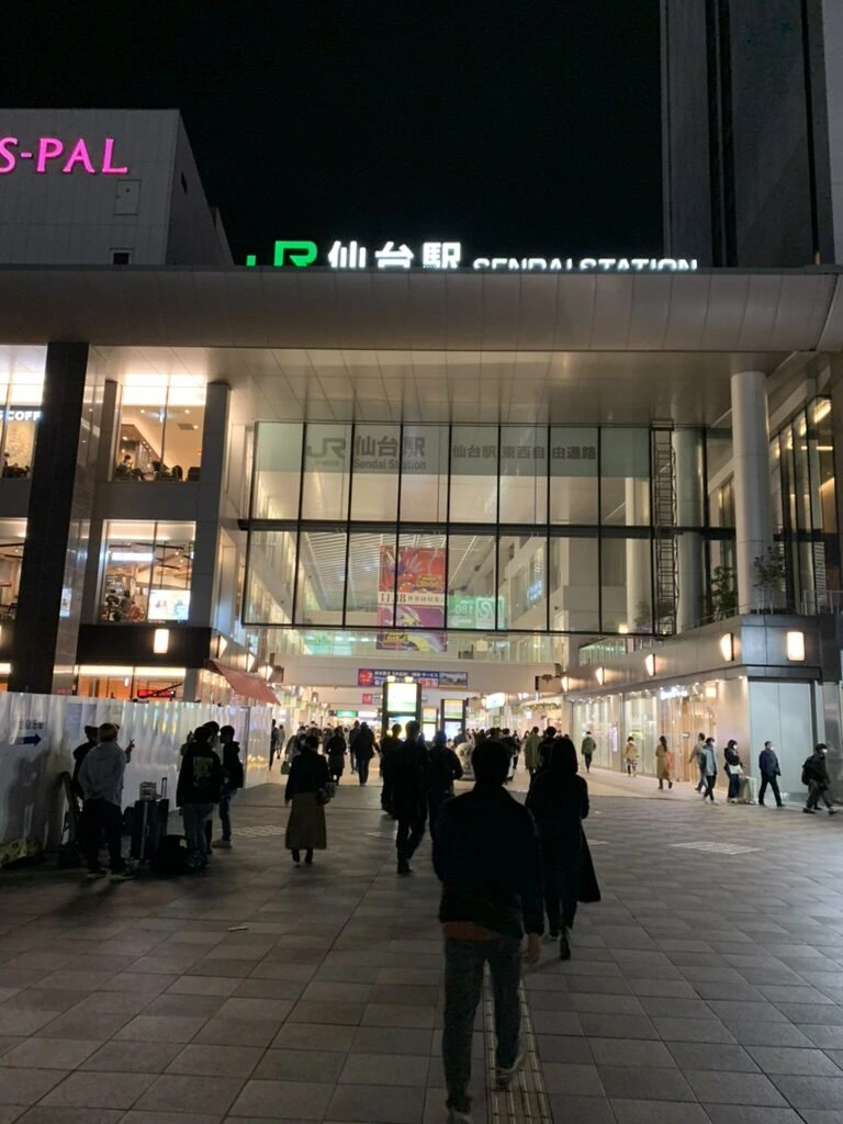 夜のJR仙台駅西口。駅舎の入口と歩く人の後ろ姿
