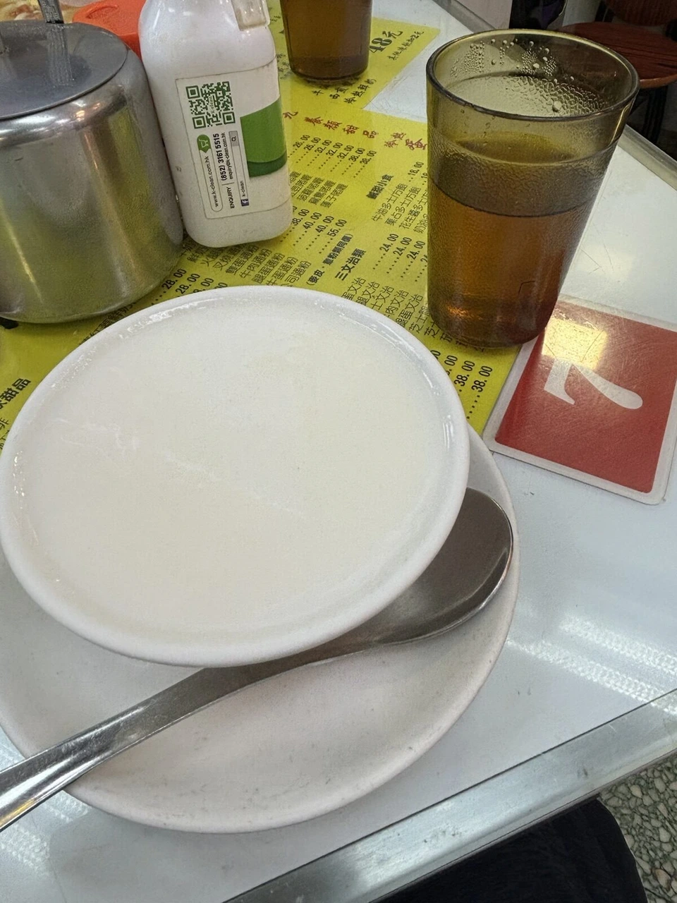香港の店の白いお粥と、黄色い紙のメニューが敷かれたテーブル