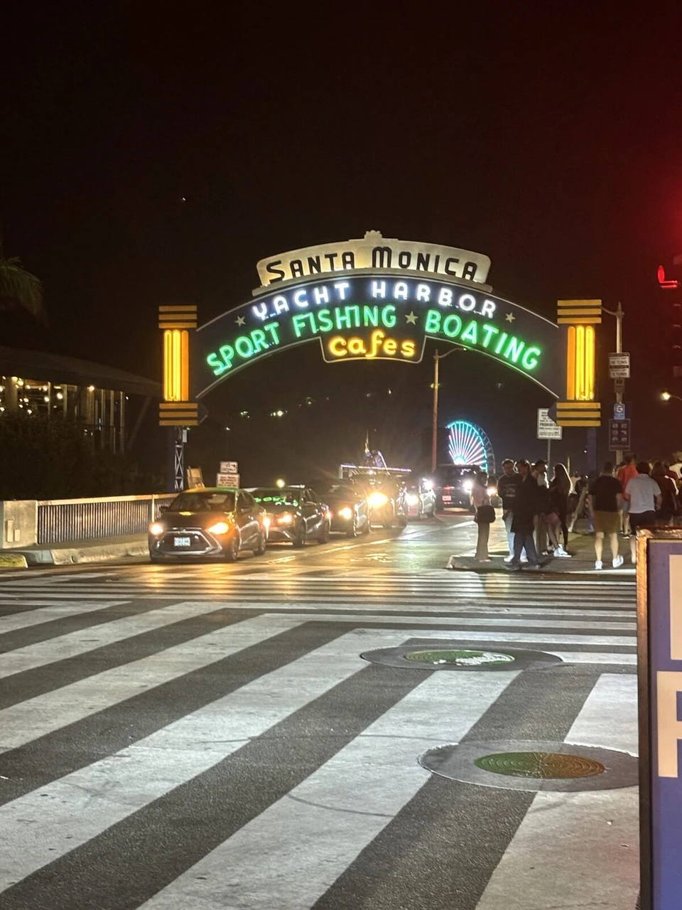 夜のサンタモニカ・ピアの入口。SANTA MONICA YACHT HARBORのネオンのアーチと横断歩道