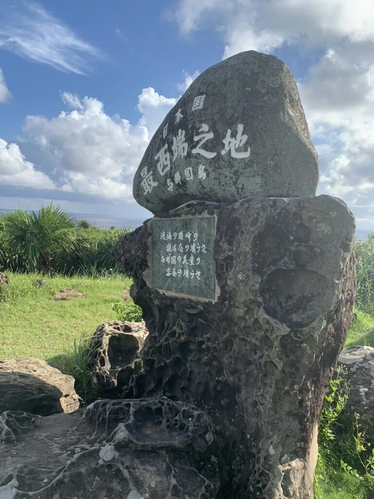 下から見上げた日本国最西端之地の碑と、雲の多い空