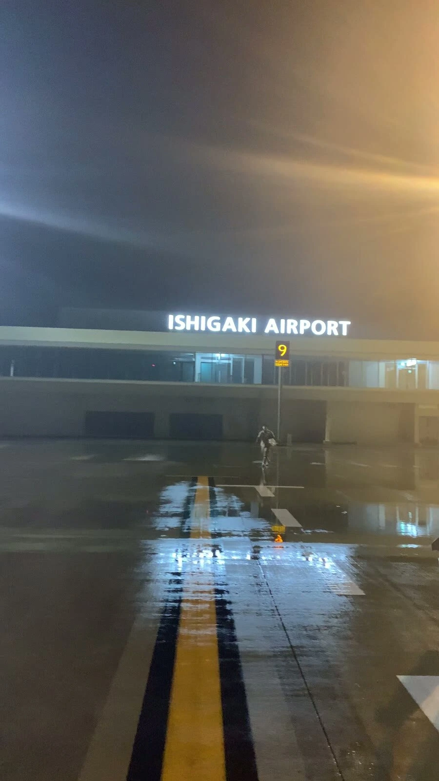 夜の石垣空港。濡れた駐機場に光が映り、ターミナルにISHIGAKI AIRPORTの文字