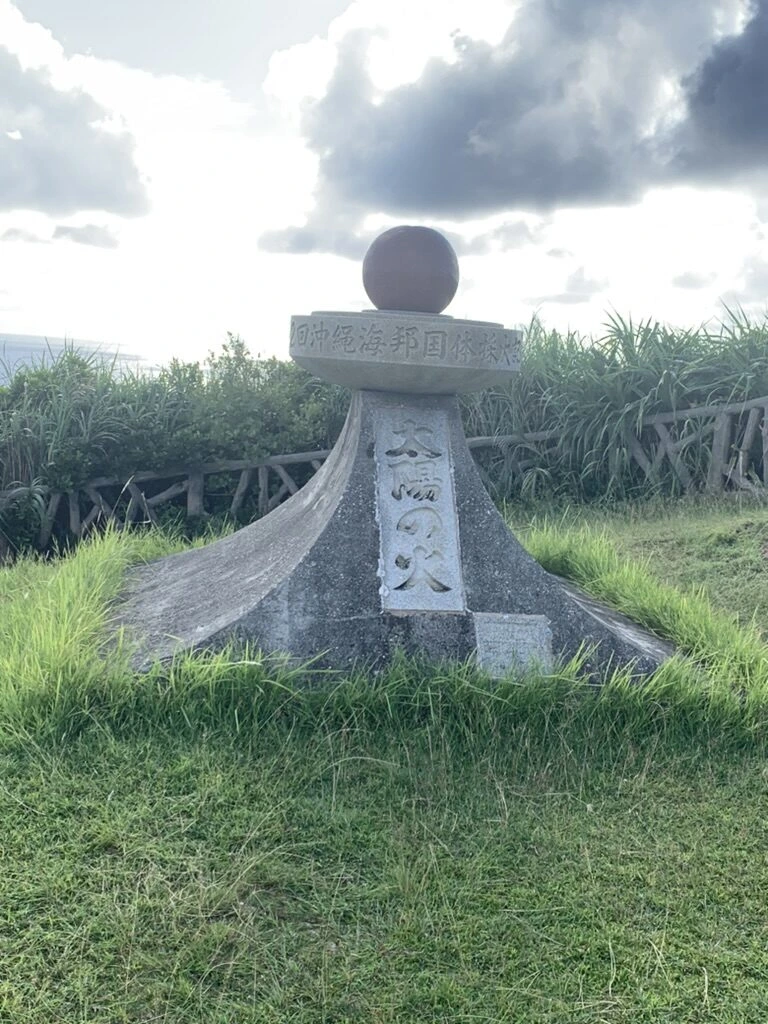 西崎の球体をのせた石の記念碑と、まわりの草地