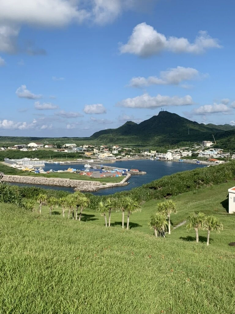 与那国島・西崎の草地から見下ろした久部良の港と集落、奥の緑の山